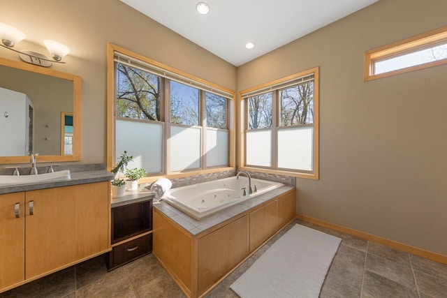 bathroom featuring a tub with jets, vanity, baseboards, and recessed lighting