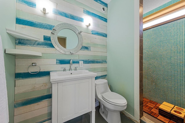 full bathroom featuring toilet, vanity, tiled shower, and wooden walls