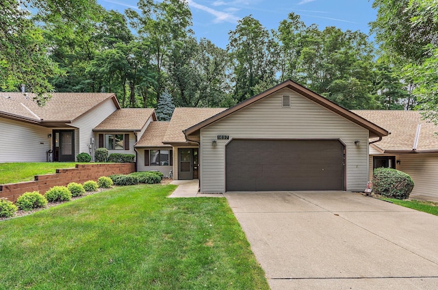 single story home with a garage, driveway, a shingled roof, and a front lawn