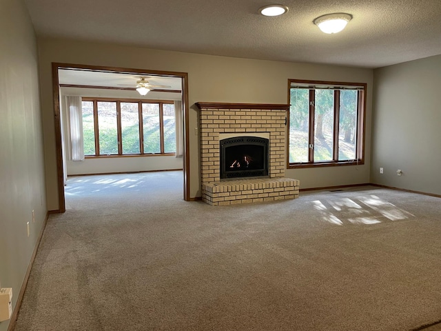 unfurnished living room with a textured ceiling, a brick fireplace, carpet flooring, and baseboards