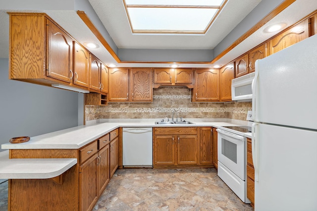 kitchen with brown cabinets, tasteful backsplash, a sink, white appliances, and a peninsula