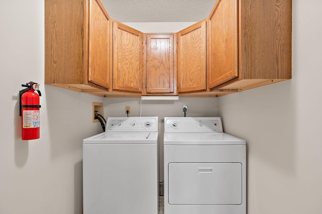 laundry area with cabinet space, independent washer and dryer, and a textured ceiling