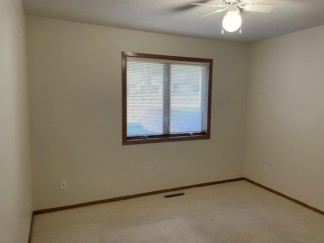 spare room with carpet floors, visible vents, ceiling fan, a textured ceiling, and baseboards