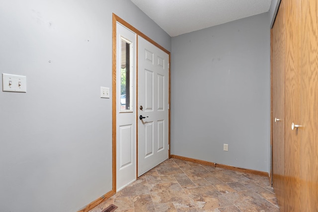 entrance foyer with stone finish flooring and baseboards