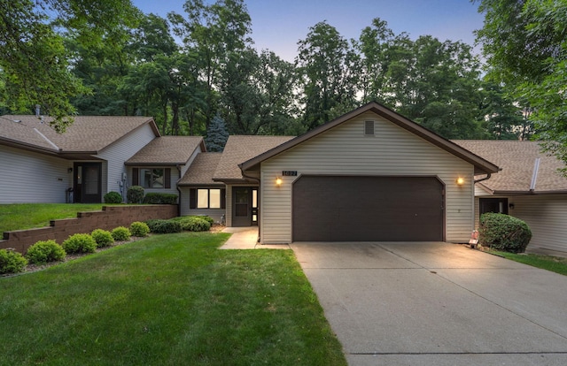 ranch-style home featuring a garage, driveway, a front lawn, and roof with shingles