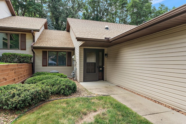 view of exterior entry featuring a shingled roof