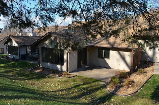 rear view of house with a patio area, a lawn, and roof with shingles