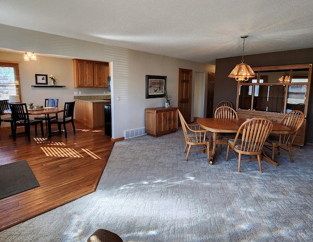 dining room featuring visible vents, a textured ceiling, baseboards, and wood finished floors