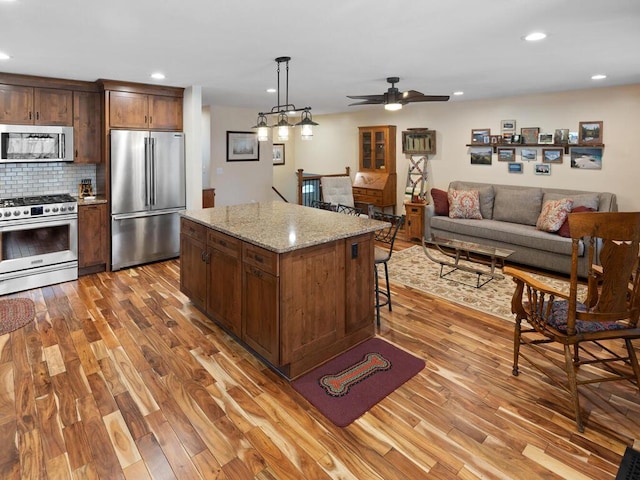 15015 Vermillion Cir NE, Andover, MN 55304 - kitchen with stainless steel appliances, wood finished floors, recessed lighting, open floor plan, and tasteful backsplash