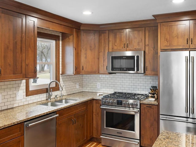 15015 Vermillion Cir NE, Andover, MN 55304 - kitchen featuring stainless steel appliances, a sink, light stone countertops, tasteful backsplash, and brown cabinets