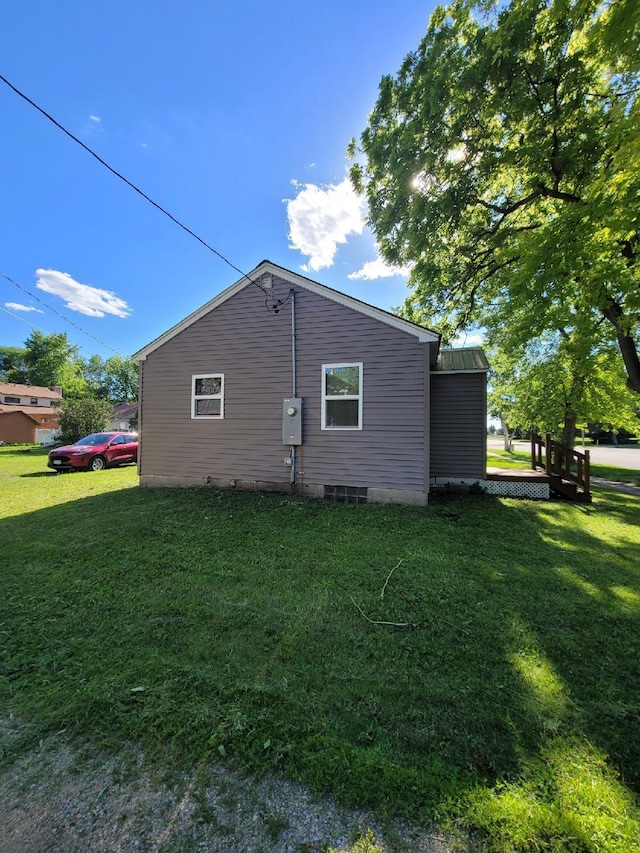 view of side of home with metal roof and a yard