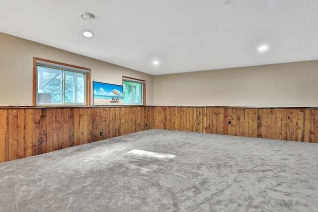 carpeted empty room featuring wooden walls, recessed lighting, and a wainscoted wall