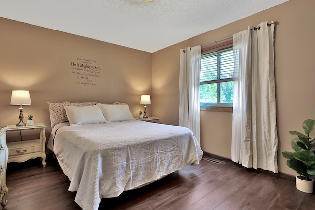 bedroom featuring dark wood-style floors, baseboards, and a textured ceiling