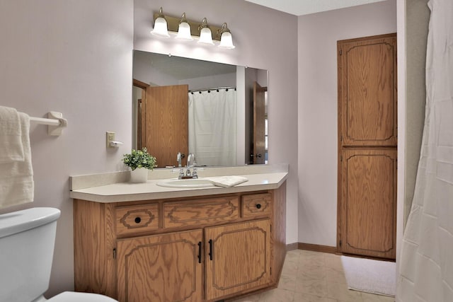 bathroom with toilet, vanity, and baseboards