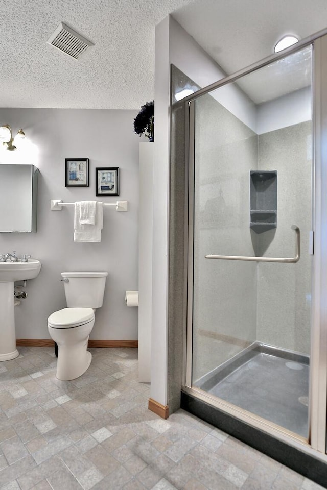 full bath featuring visible vents, a shower stall, baseboards, toilet, and a textured ceiling