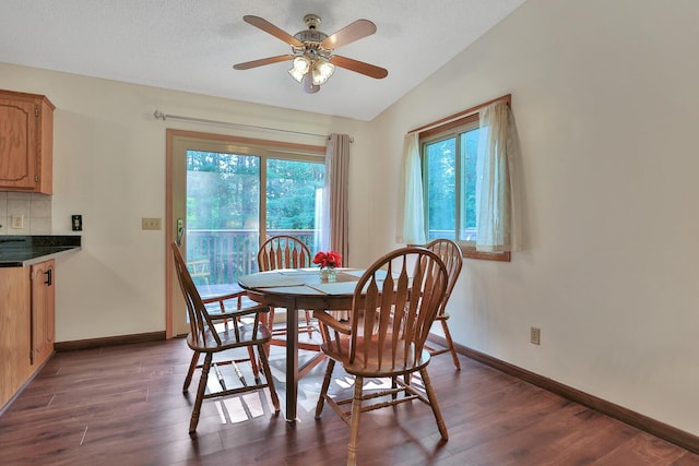 dining room featuring dark wood-type flooring, baseboards, lofted ceiling, and ceiling fan