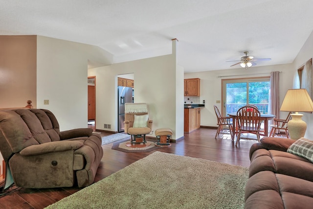 living area with baseboards, dark wood-type flooring, ceiling fan, and vaulted ceiling