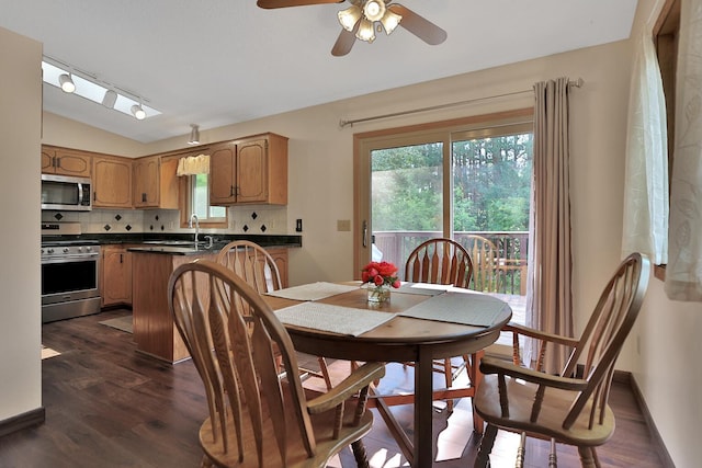 dining room with dark wood-type flooring, lofted ceiling, track lighting, a ceiling fan, and baseboards