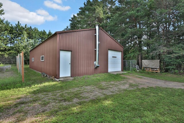 view of outdoor structure featuring an outbuilding, driveway, and fence