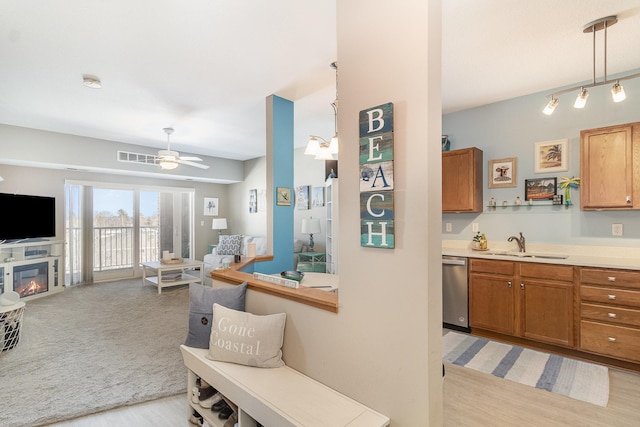 kitchen featuring open floor plan, light countertops, a sink, and stainless steel dishwasher