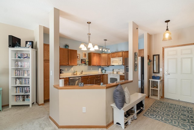 kitchen with a chandelier, stainless steel appliances, a sink, brown cabinets, and decorative light fixtures