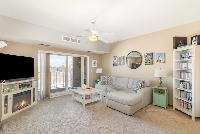 carpeted living room featuring ceiling fan, a glass covered fireplace, and visible vents