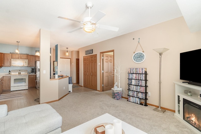 living room with baseboards, visible vents, a ceiling fan, a glass covered fireplace, and light colored carpet