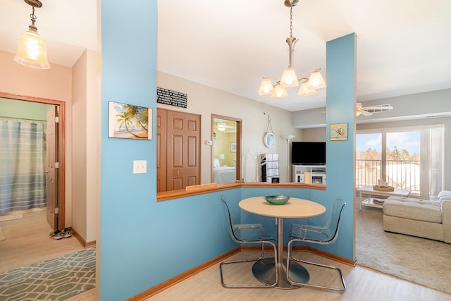 dining area featuring a notable chandelier, baseboards, and wood finished floors