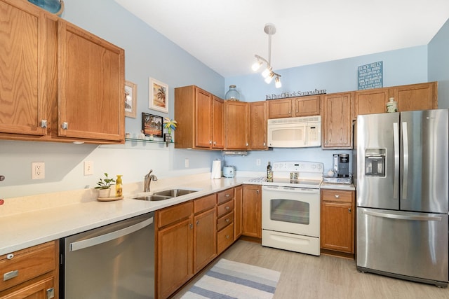 kitchen featuring brown cabinets, light countertops, appliances with stainless steel finishes, light wood-style floors, and a sink