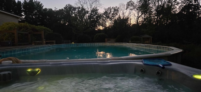 pool at dusk featuring an outdoor pool and a jacuzzi