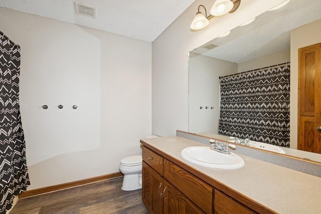 bathroom featuring visible vents, toilet, wood finished floors, baseboards, and vanity