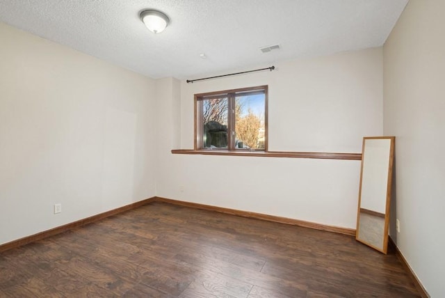 spare room with a textured ceiling, baseboards, and wood finished floors