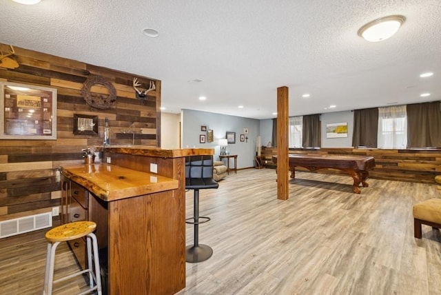 bar with visible vents, bar area, wooden walls, and wood finished floors