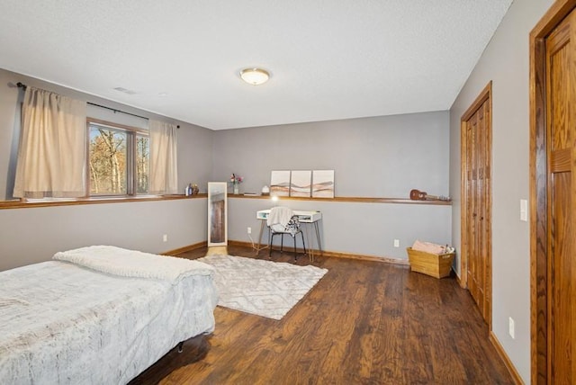 bedroom with baseboards, a textured ceiling, and wood finished floors