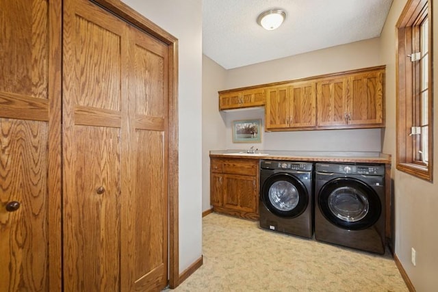 laundry room featuring light carpet, washer and dryer, a sink, cabinet space, and baseboards