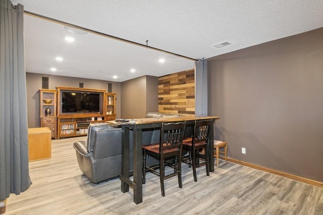 living room with a dry bar, recessed lighting, baseboards, and light wood finished floors