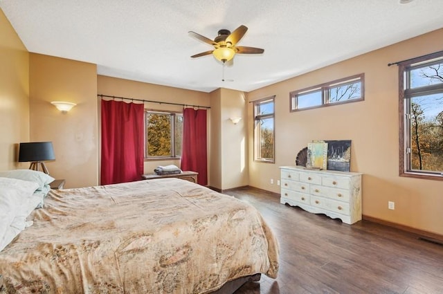 bedroom featuring ceiling fan, visible vents, baseboards, and wood finished floors