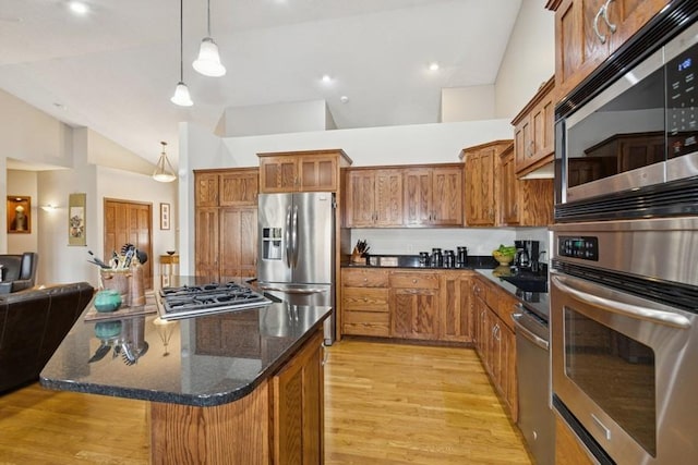 kitchen featuring brown cabinets, pendant lighting, light wood-style flooring, a center island, and appliances with stainless steel finishes