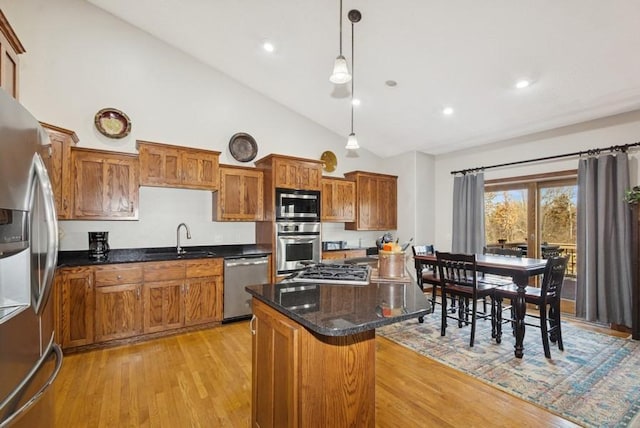 kitchen with a center island, light wood-style floors, brown cabinetry, stainless steel appliances, and a sink