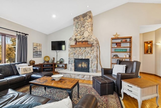 living area featuring a stone fireplace, wood finished floors, and high vaulted ceiling