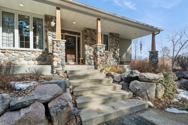 doorway to property with stone siding and covered porch