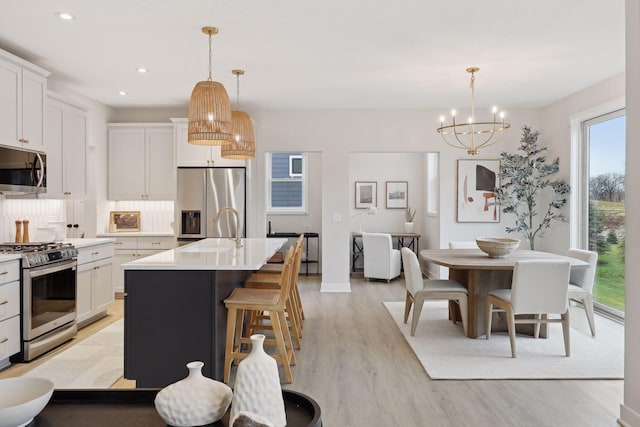 4640 Meadowview Ln, Minnetrista, MN 55331 - kitchen with appliances with stainless steel finishes, a chandelier, light wood finished floors, light countertops, and white cabinets
