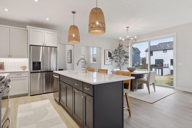 4640 Meadowview Ln, Minnetrista, MN 55331 - kitchen with appliances with stainless steel finishes, light wood-style flooring, light countertops, white cabinets, and pendant lighting