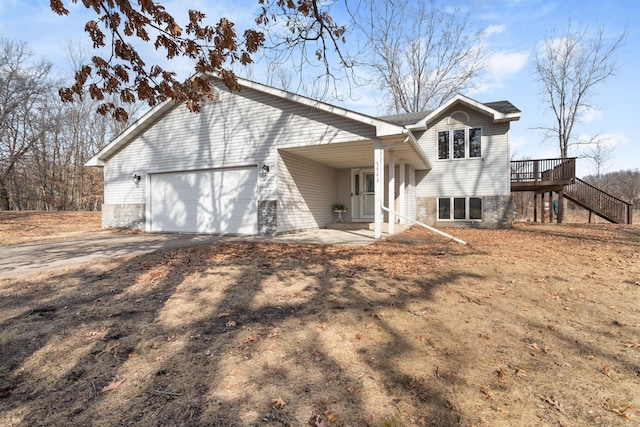 exterior space featuring stairway, driveway, an attached garage, and a deck