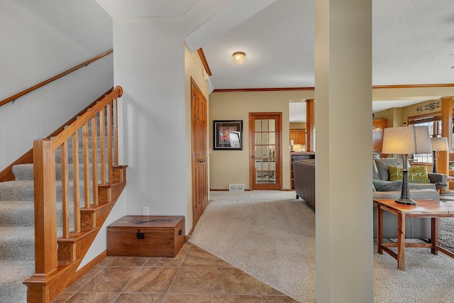 hallway with visible vents, baseboards, stairway, ornamental molding, and carpet floors