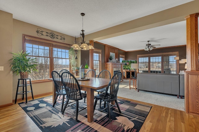 dining space featuring wood finished floors, plenty of natural light, a fireplace, and ornate columns