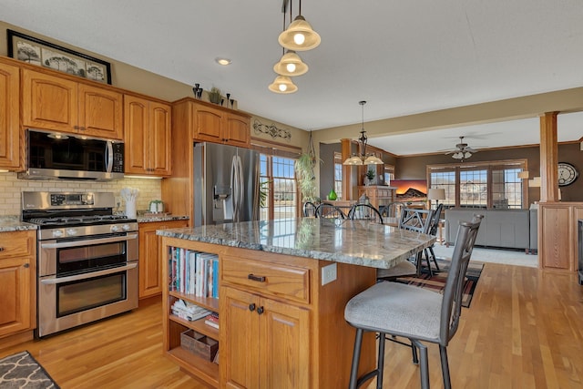 kitchen with a kitchen breakfast bar, a healthy amount of sunlight, stone counters, and stainless steel appliances