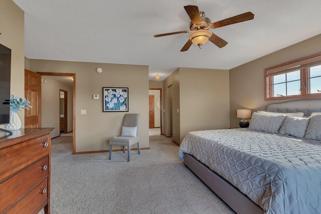 bedroom featuring baseboards, light carpet, a textured ceiling, and a ceiling fan