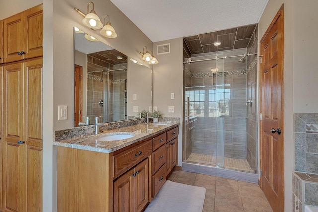 bathroom with a sink, visible vents, double vanity, and a shower stall