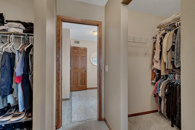 walk in closet featuring visible vents and light colored carpet